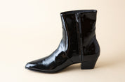 Black patent leather boot on a beige background