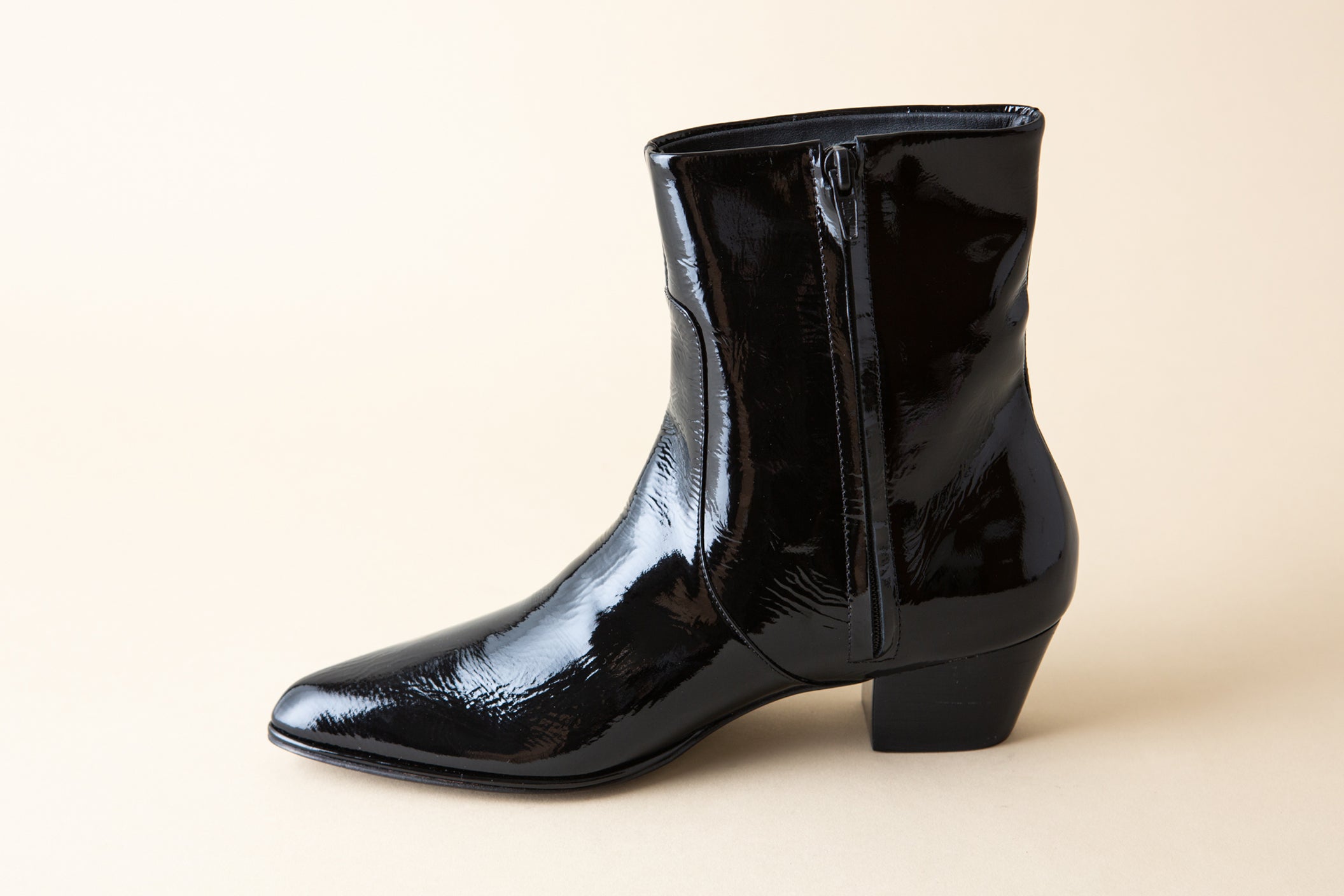 Black patent leather boot on a beige background