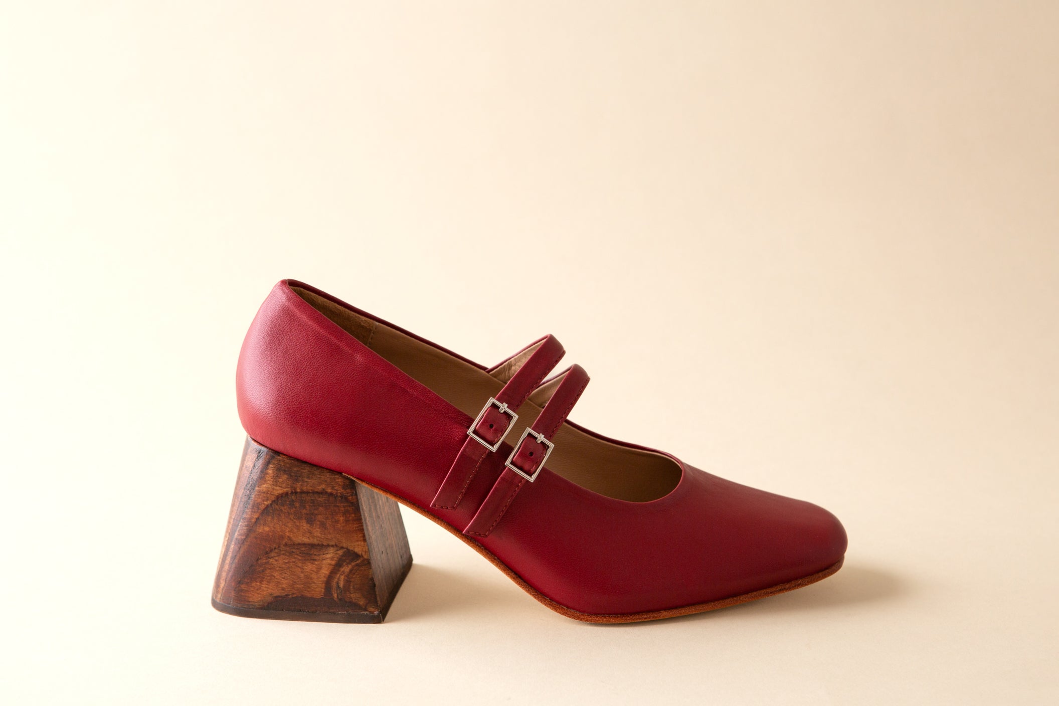 Red shoe with wooden block heel on a beige background