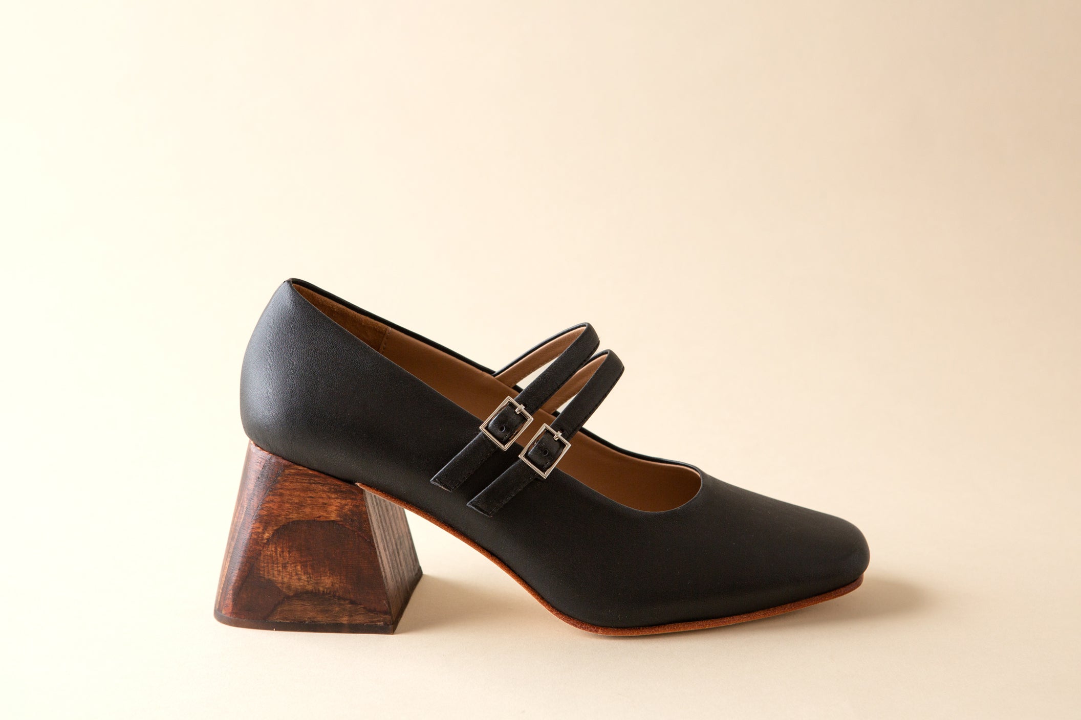 Black shoe with wooden heel on a beige background