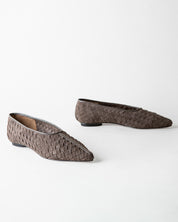 A pair of pointed-toe flat shoes with a woven basket-like texture in a dark taupe-brown color, displayed on a clean white background.